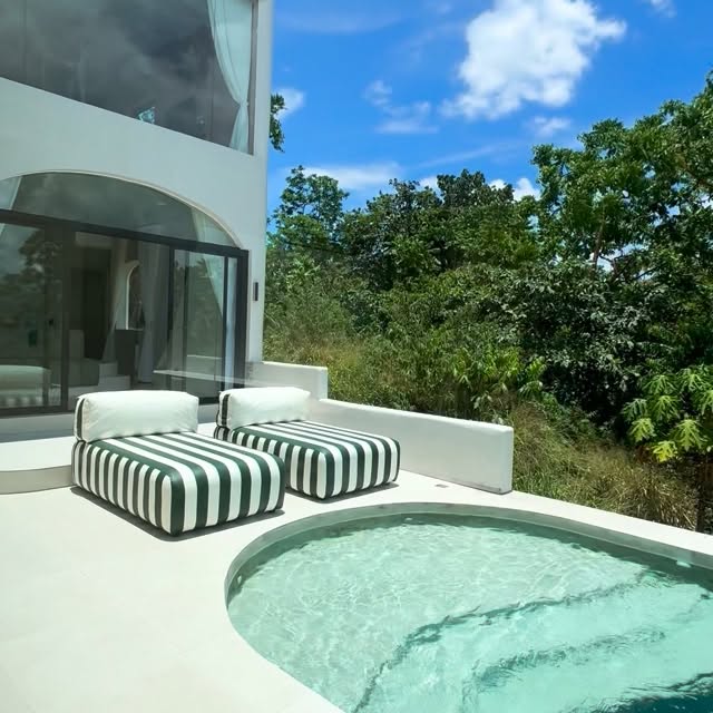 Pool deck with green-striped sun loungers and round jacuzzi